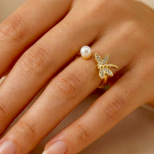 Gold ring with a pearl and butterfly design on a hand